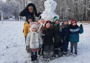 Słoneczka z grupy VI wraz z nauczycielem prezentują ulepionego ze śniegu bałwana